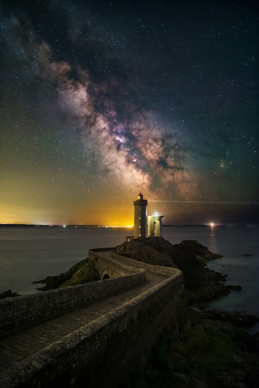 Lighthouse on a rocky coast at night under a starry sky