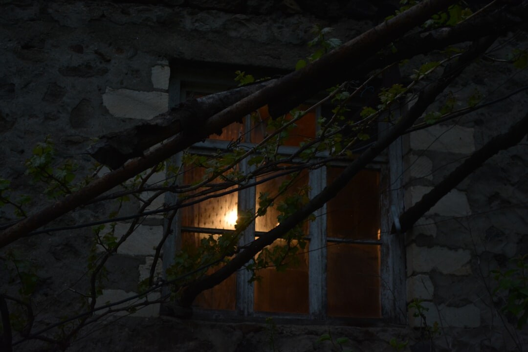 Old stone building window glowing with candlelight at night